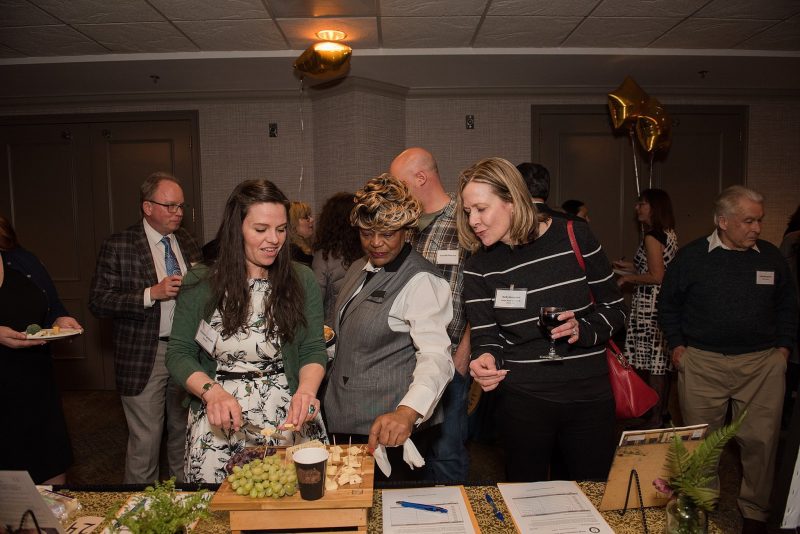 women looking at grape and cheese plate at event