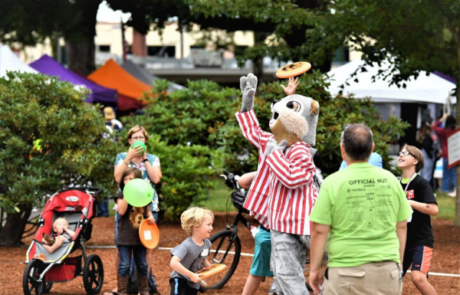 person dressed up as squirrel in red and white striped jacket surrounded by kids